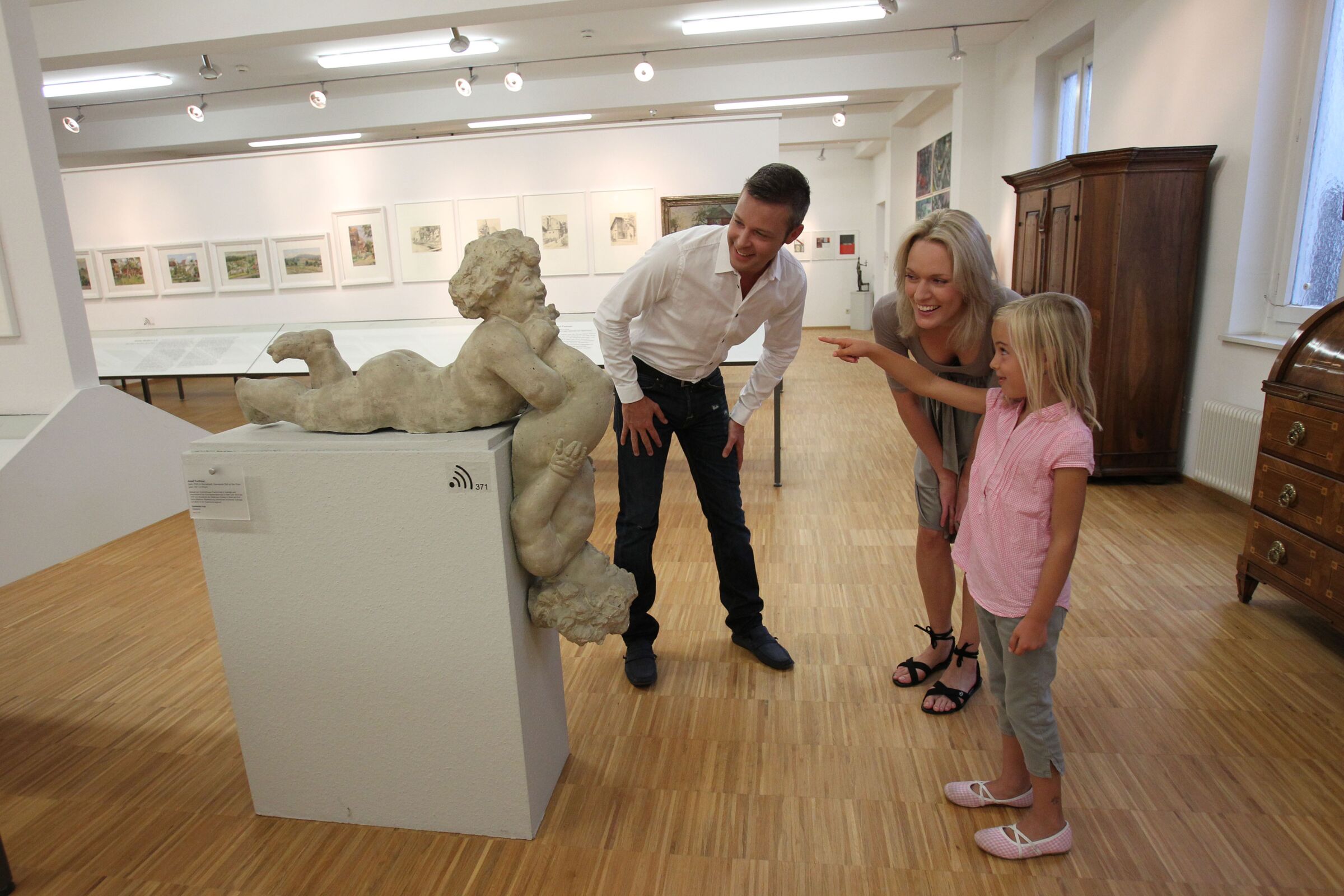 Eine Familie im Rieder volkskunde Haus besichtigt eine Statue.