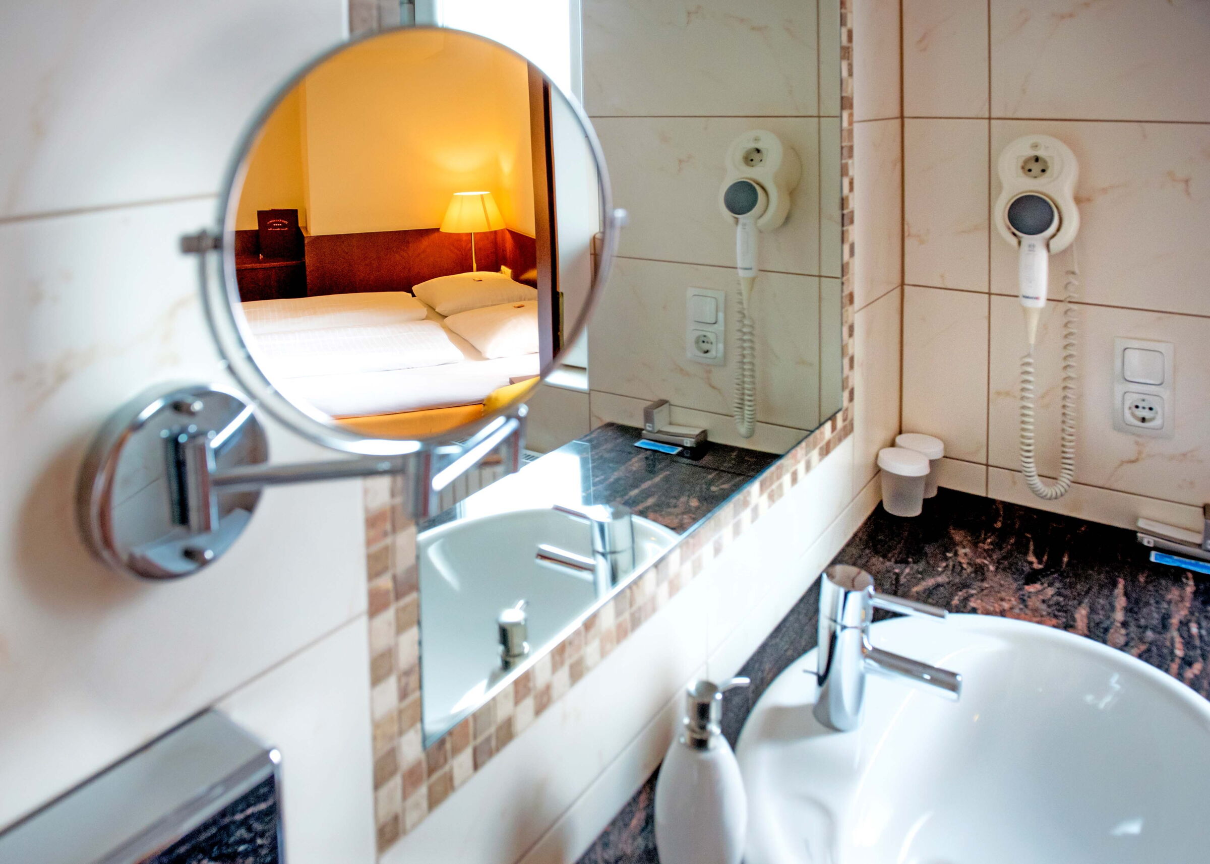 The mirror in the bathroom reflects the box-spring bed opposite in the Classic double room at Hotel Der Kaiserhof