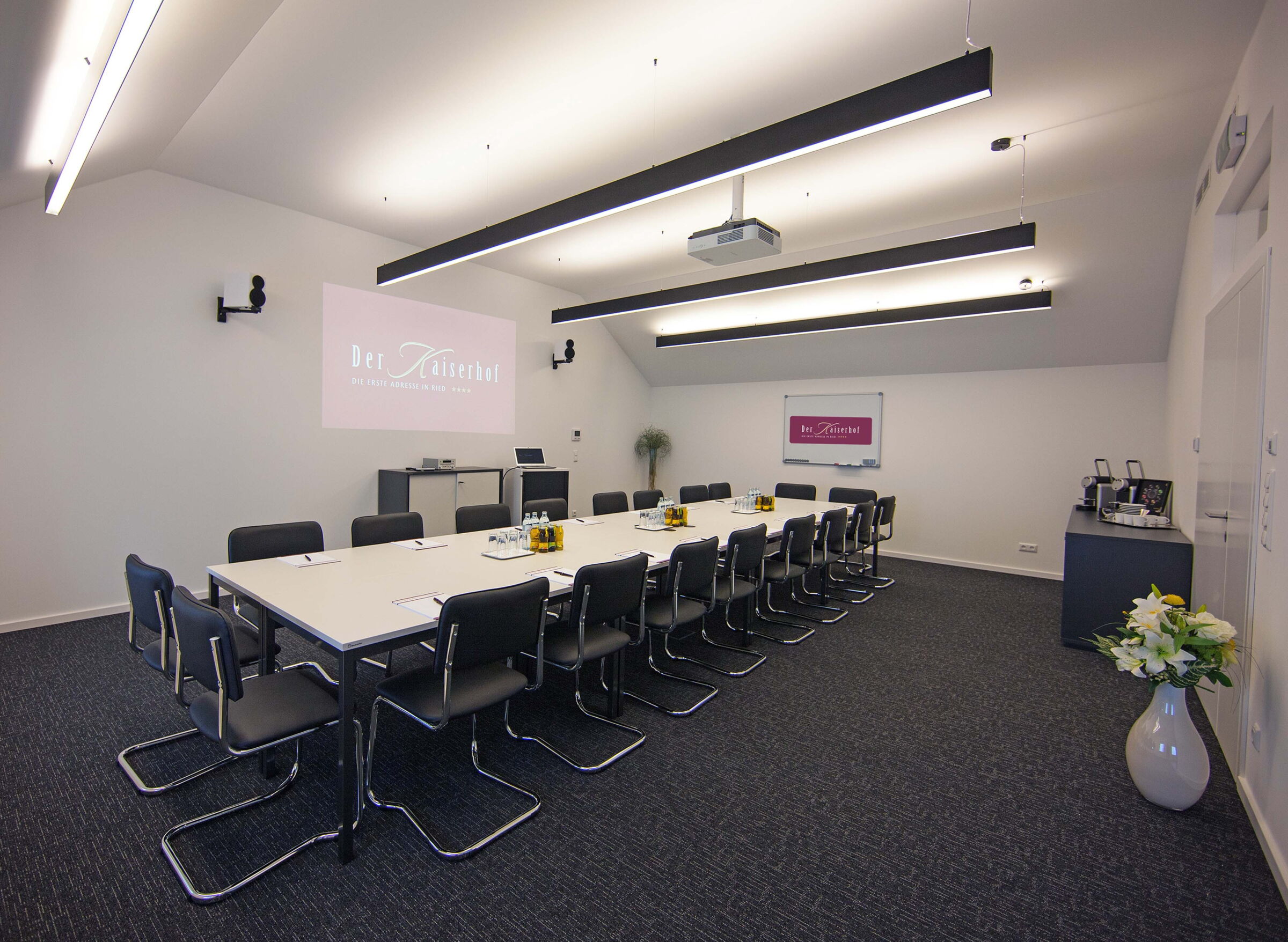 The spacious seminar room at Hotel Der Kaiserhof in Ried with projector and bright ceiling lighting