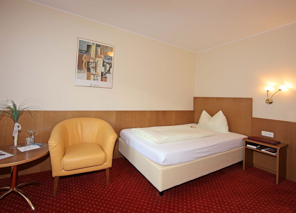 The Classic single room with box-spring bed and red carpeting in classic style at Hotel Der Kaiserhof