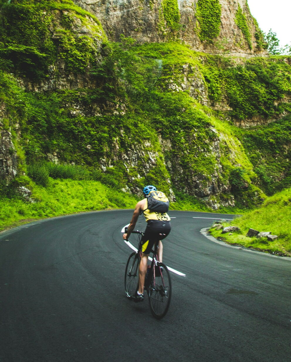 A man rides a bicycle up a hill on a road