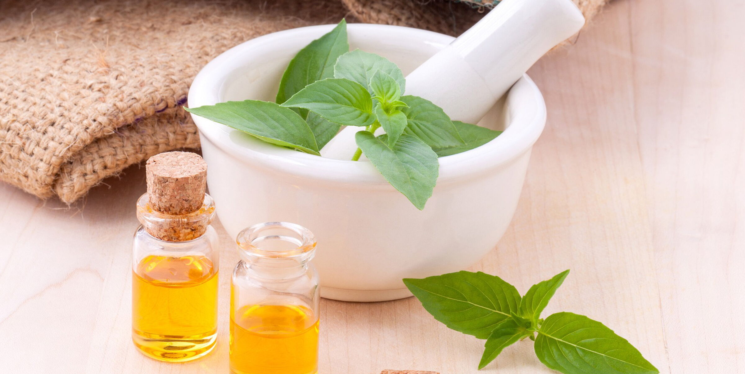 Two massage oils and a mortar containing plants.