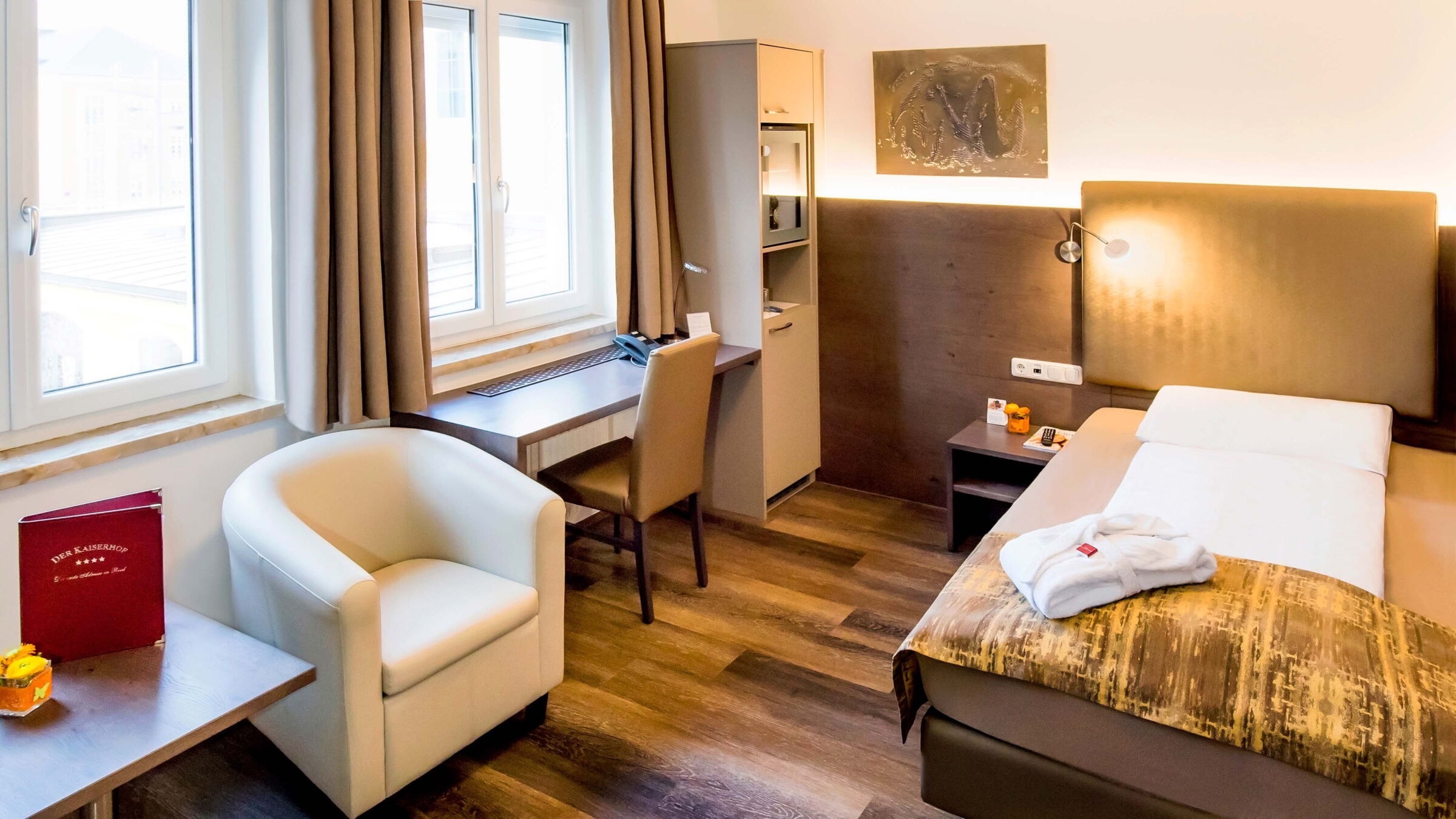 Das Business-Einzelzimmer mit Holzboden, Boxspringbett und Schreibtisch mit Blick auf den Garten im Hotel Der Kaiserhof