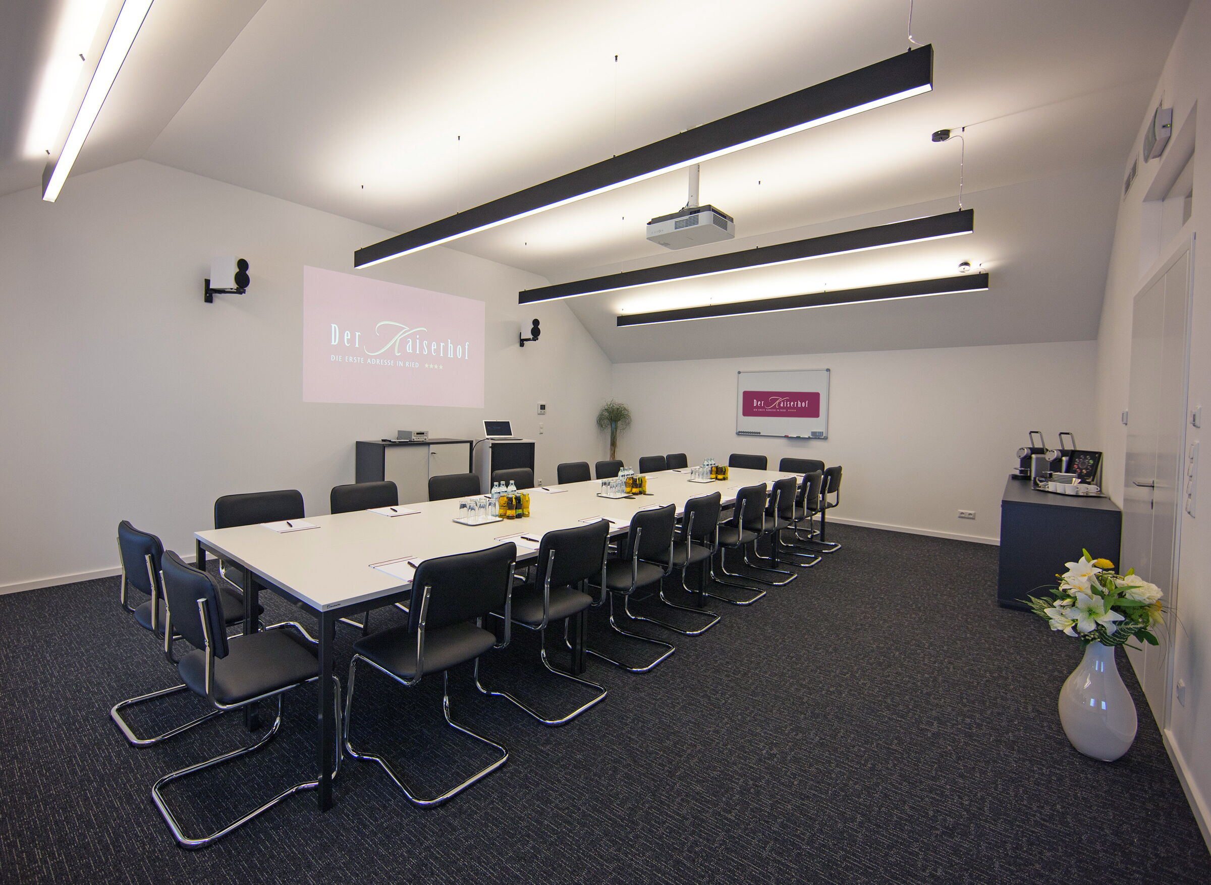 The spacious seminar room at Hotel Der Kaiserhof in Ried with projector and bright ceiling lighting