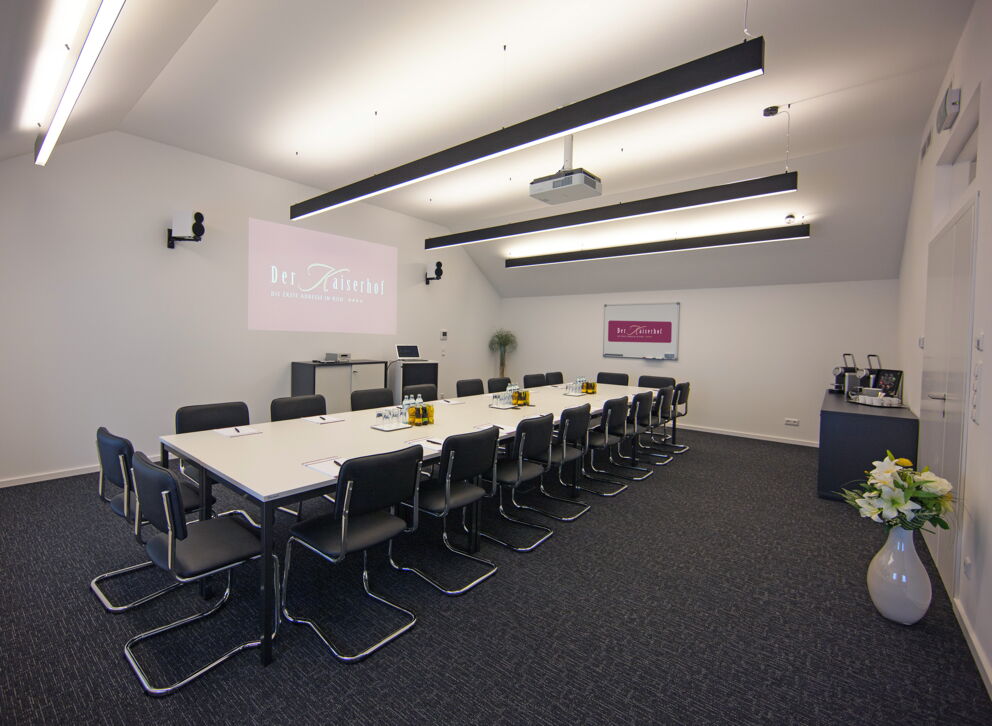 The spacious seminar room at Hotel Der Kaiserhof in Ried with projector and bright ceiling lighting