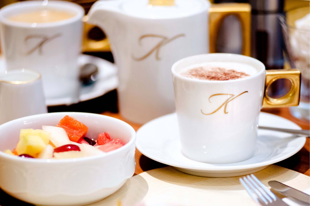 Fruit salad bowls and coffee with the Der Kaiserhof logo on the cup