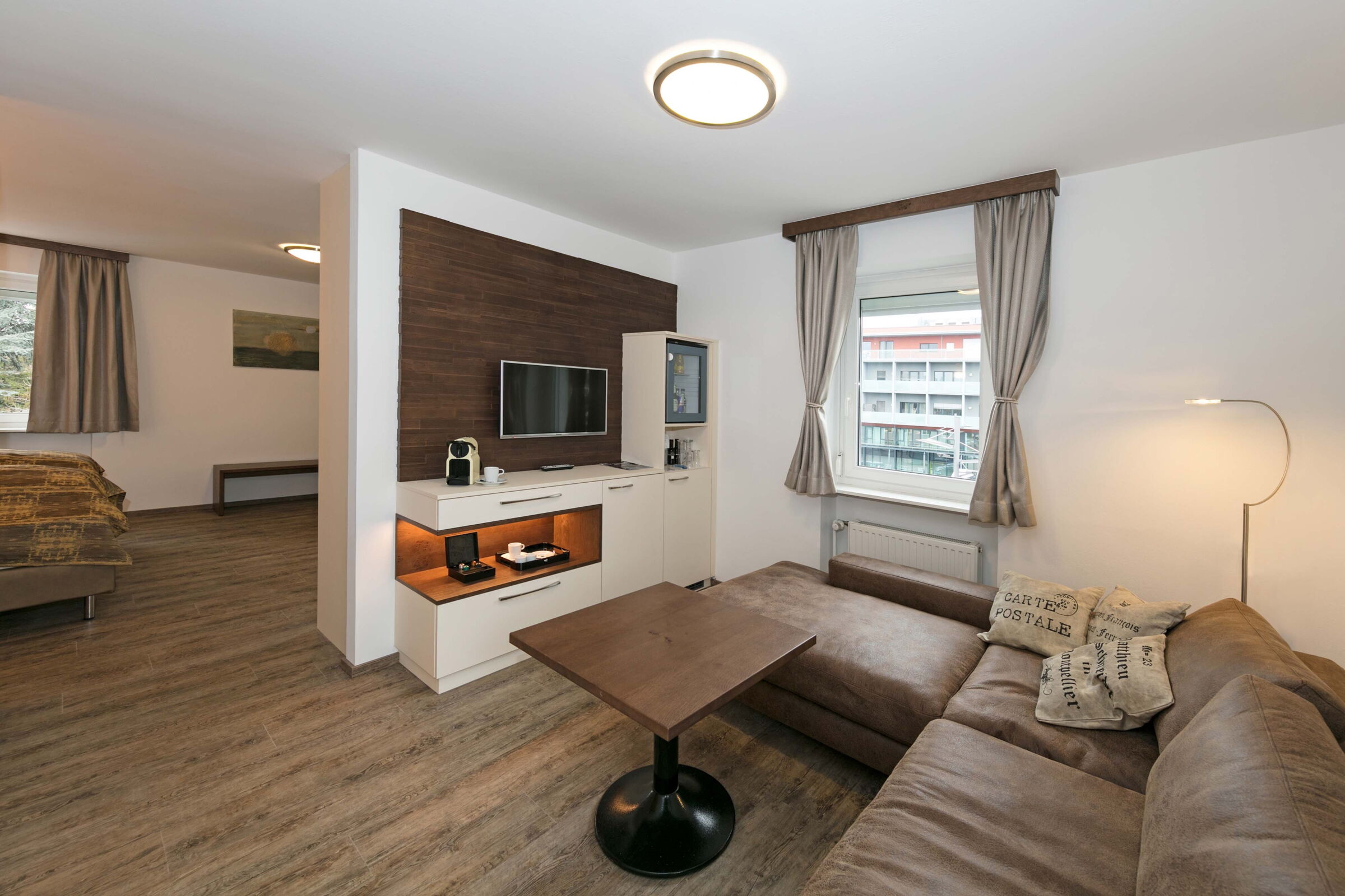 Die Business-Suite mit einer großen L-förmigen Couch, einem kleinen Tisch und einem Fernseher im Hotel Der Kaiserhof