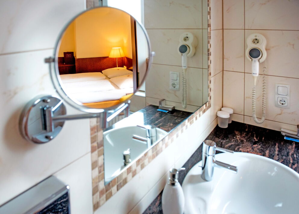 The mirror in the bathroom reflects the box-spring bed opposite in the Classic double room at Hotel Der Kaiserhof