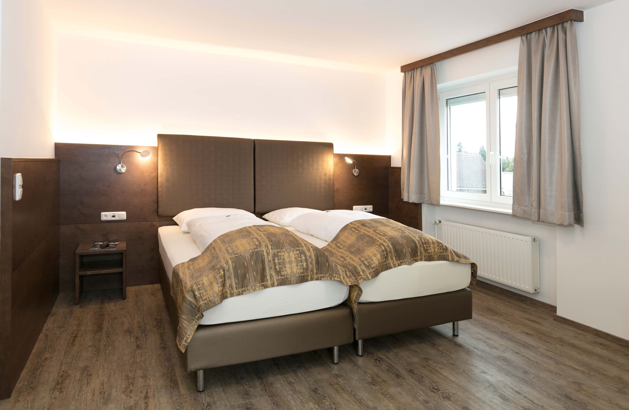 Das Schlafzimmer der Junior Suite mit einem Boxspringbett und Blick auf den Garten im Hotel Der Kaiserhof