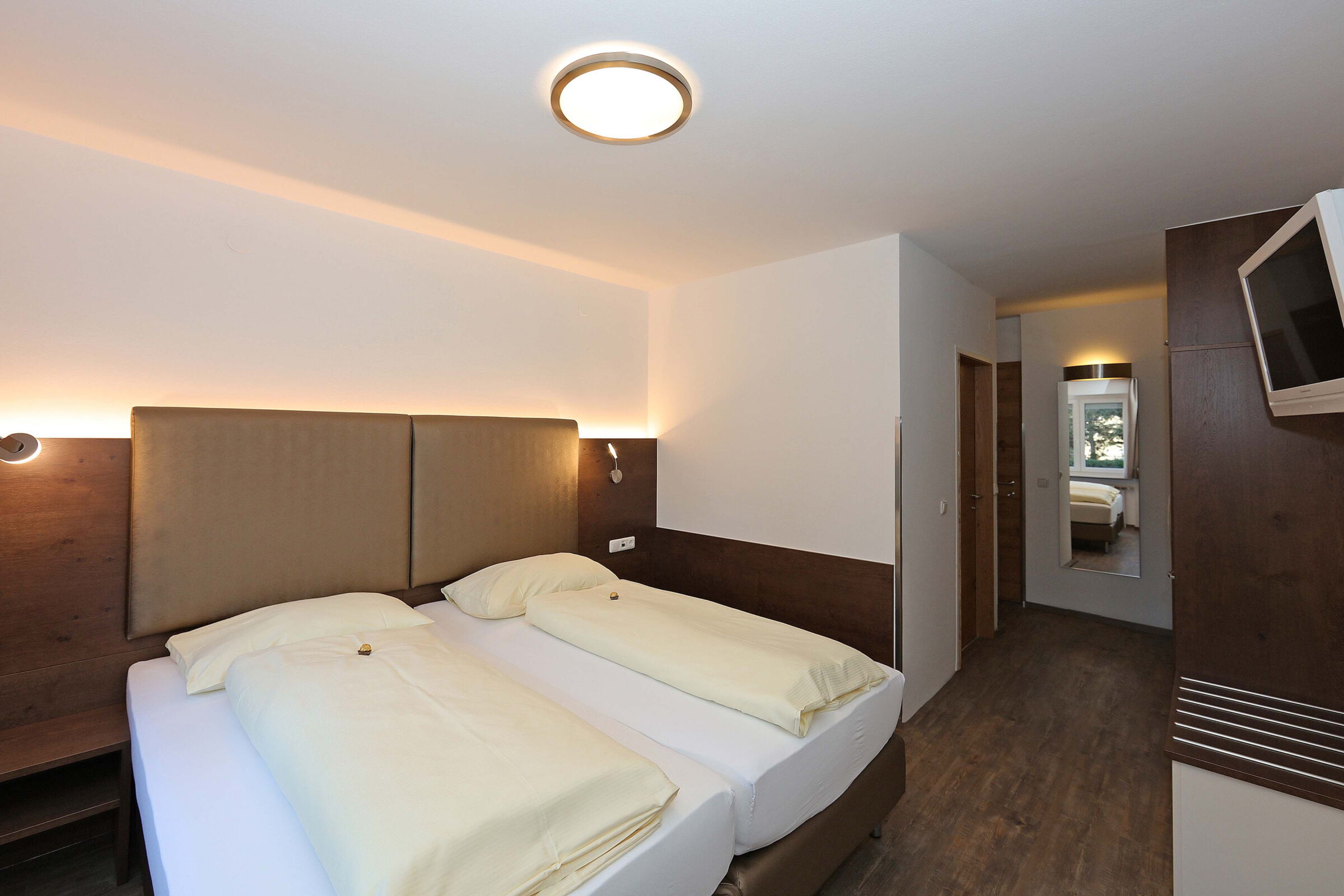 Modernes Business-Doppelzimmer mit Holzboden und Fernseher im Hotel der Kaiserhof