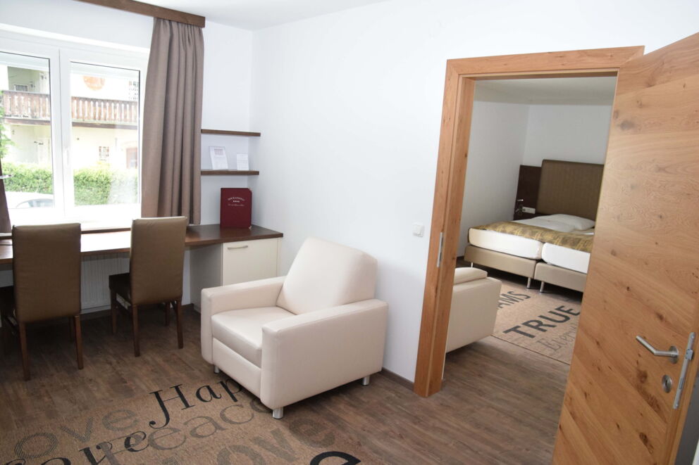 The living area of the suites with white armchairs and a table at Hotel Der Kaiserhof