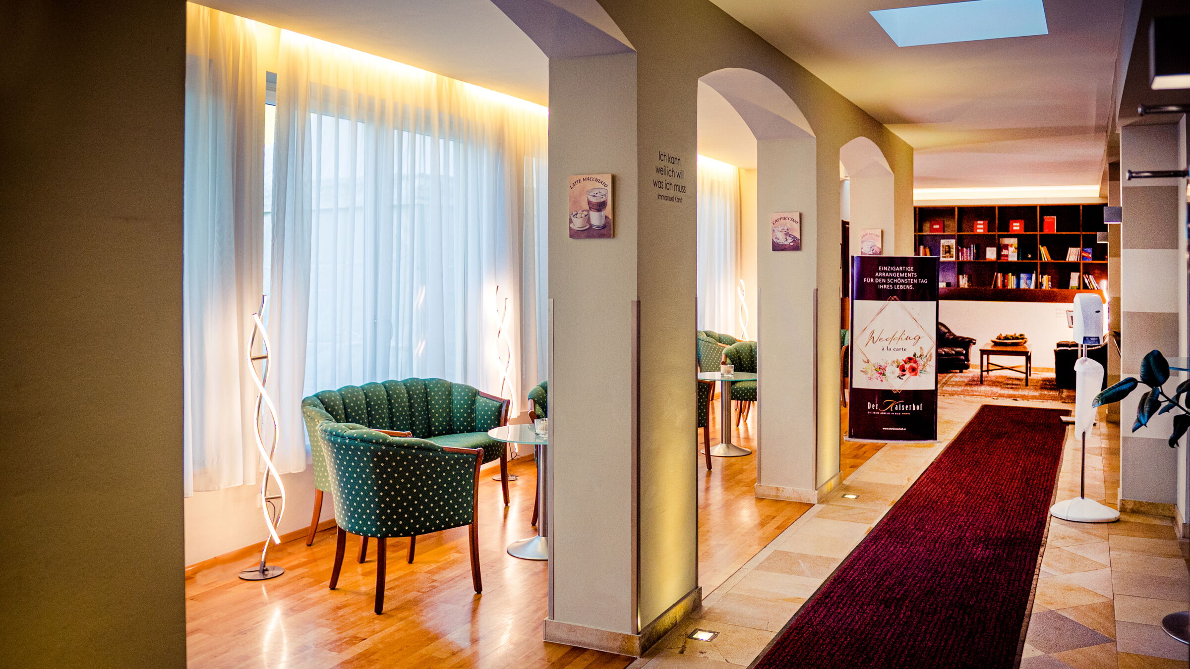 Die Hotellobby im Der Kaiserhof mit grünen Sesseln und einem roten Teppich
