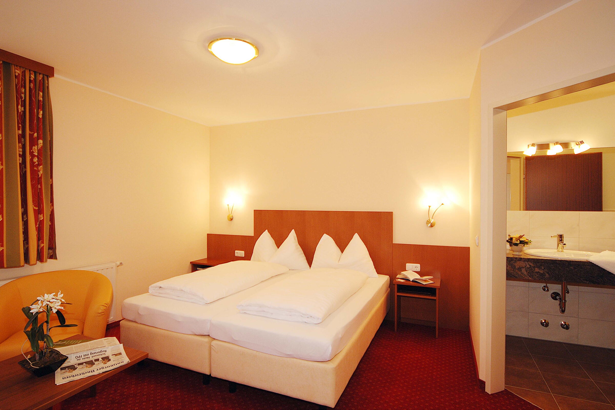 Klassisch eingerichtetes Doppelzimmer mit rotem Teppichboden und einem Boxspringbett im Hotel Der Kaiserhof