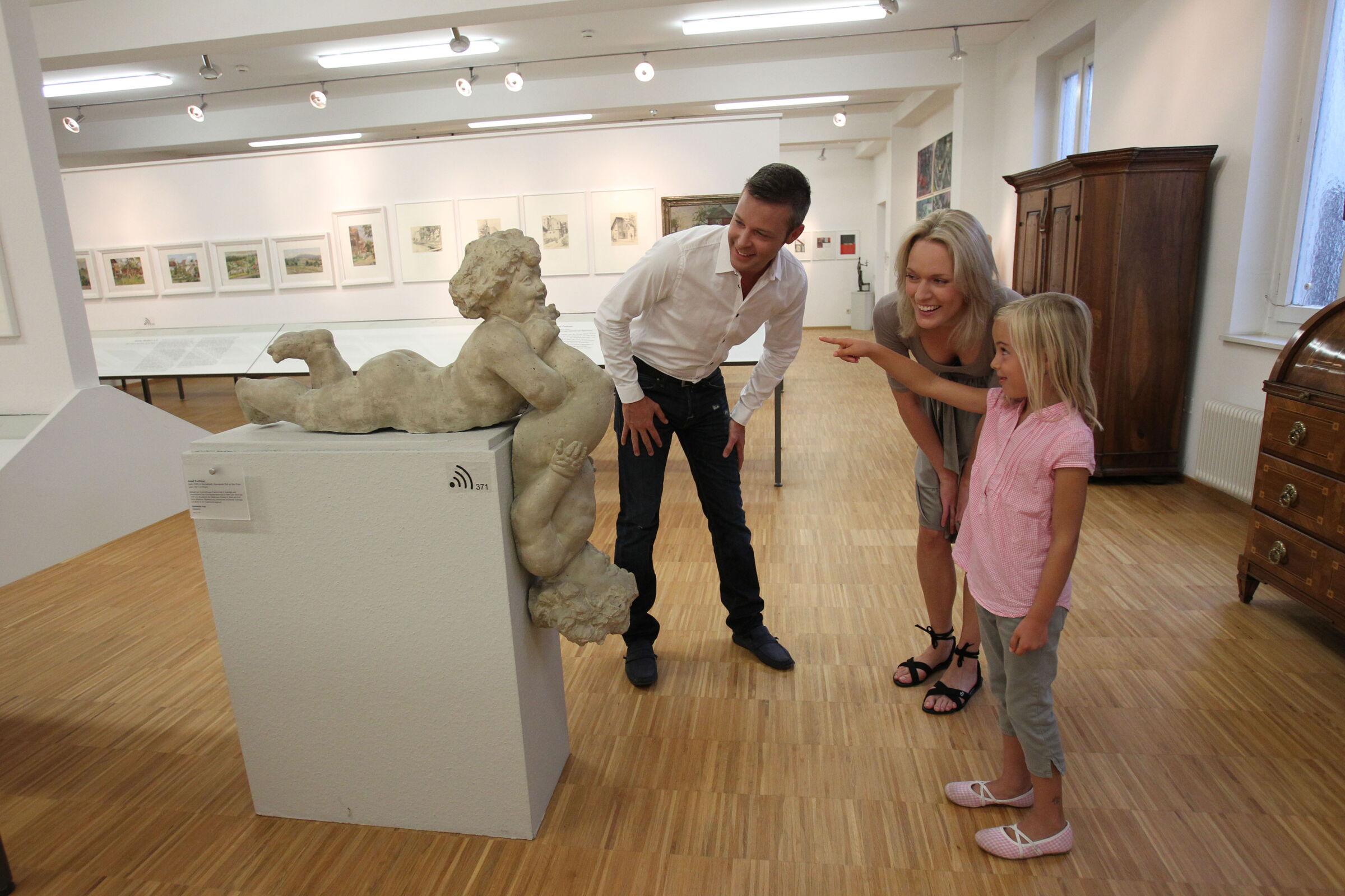 Eine Familie im Rieder volkskunde Haus besichtigt eine Statue.