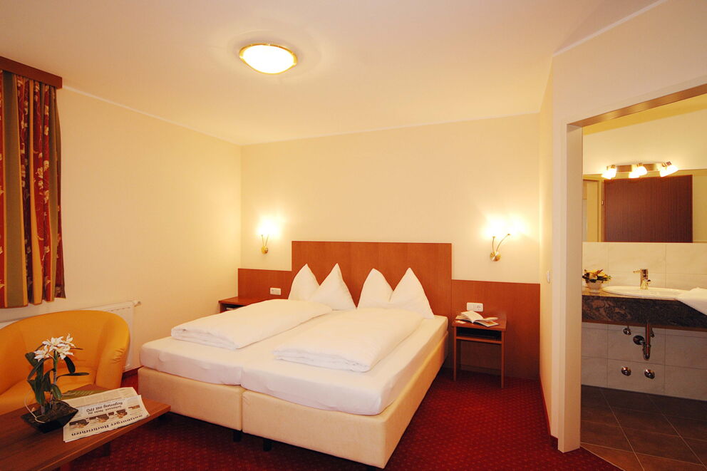 Classically furnished double room with red carpeting and a box-spring bed at Hotel Der Kaiserhof