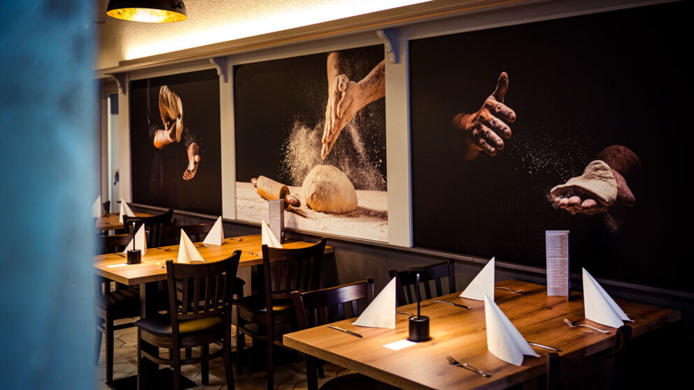 Restaurant "Da Mimmo" at Hotel Der Kaiserhof with beautifully laid tables and paintings on the wall