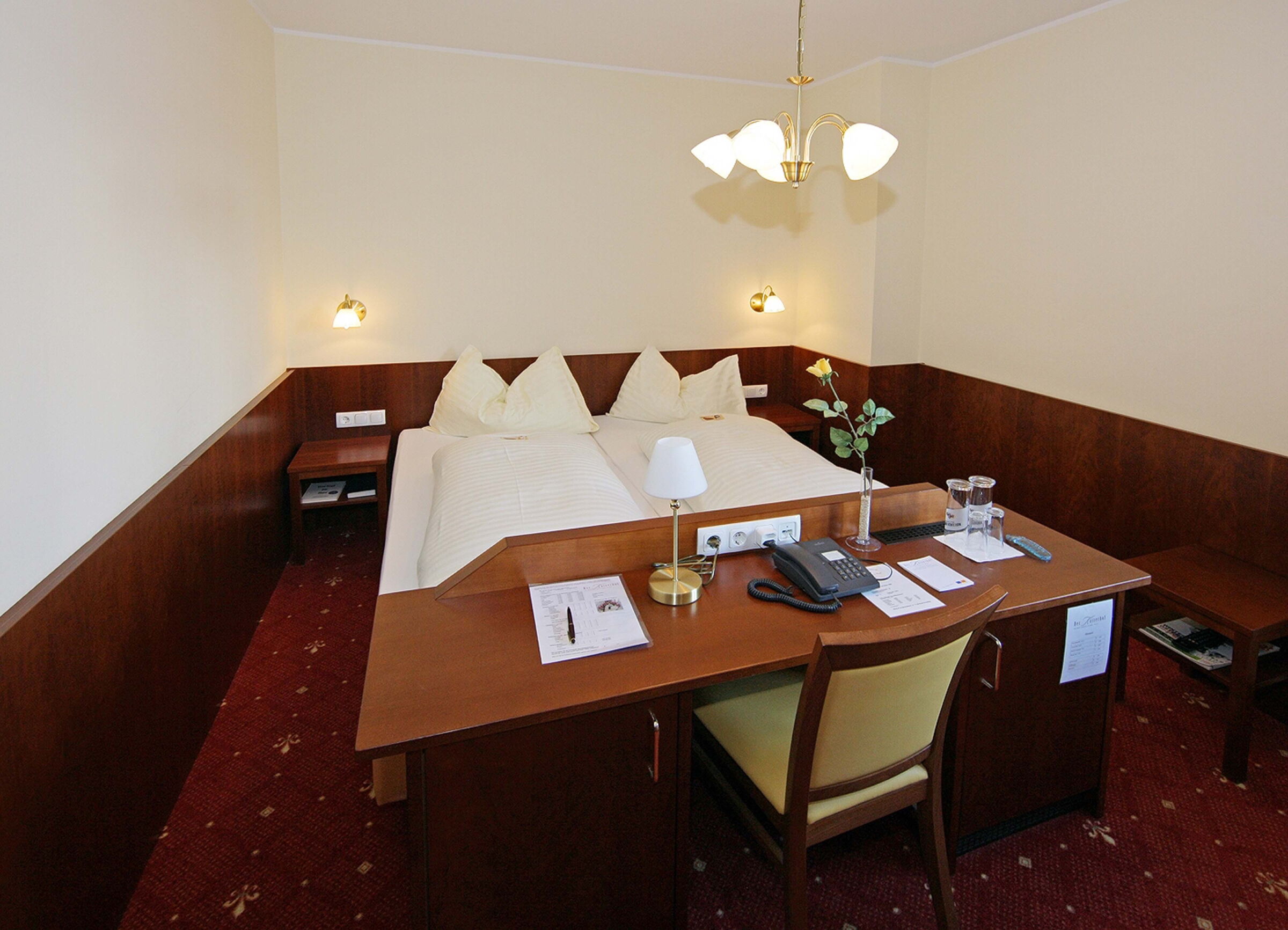 The box-spring bed in the Classic double room with desk at the end of the bed at Hotel Der Kaiserhof