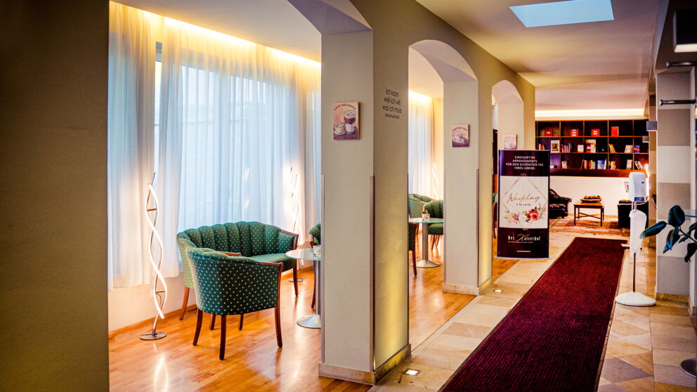 The hotel lobby at Der Kaiserhof with green armchairs and a red carpet